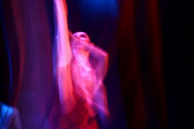 Blurred motion of person standing against illuminated light