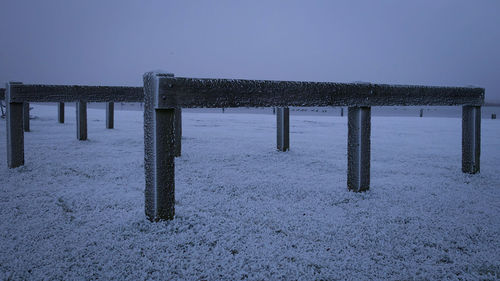 Wooden posts in sea against clear sky during winter