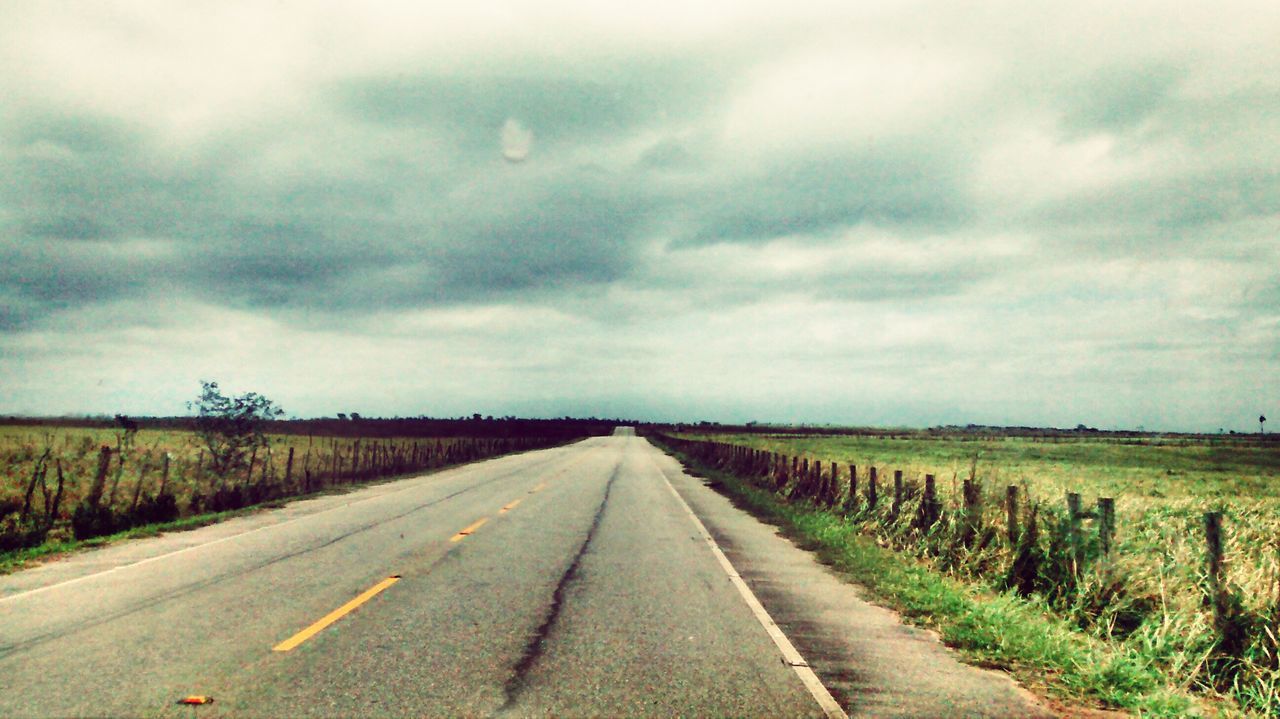 the way forward, diminishing perspective, transportation, road, vanishing point, sky, cloud - sky, cloudy, landscape, country road, road marking, field, empty road, tranquility, tranquil scene, grass, cloud, empty, nature, long