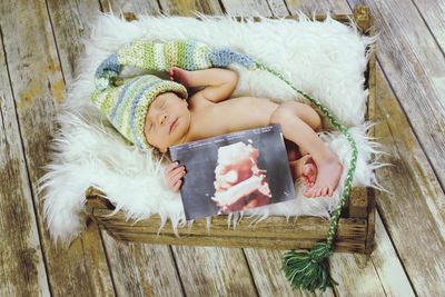 High angle view of baby lying on wooden floor