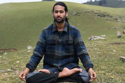 A young indian guy practicing meditation, yoga in lotus pose, padmasana in the mountain.