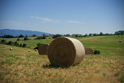 Hay bales on field against sky