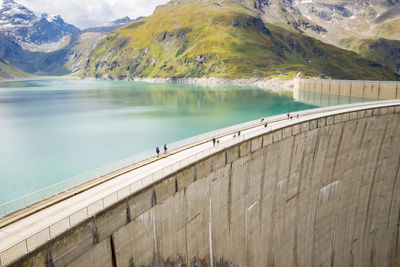 Scenic view of people walking on footbridge over lake