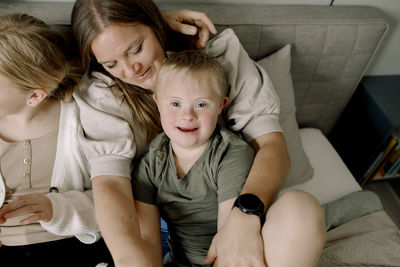 High angle portrait of boy sitting with family on bed at home