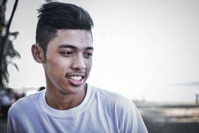 Portrait of young man standing against sky