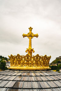 Low angle view of cross sculpture against sky