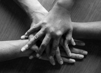 Cropped image of friends stacking hands over table