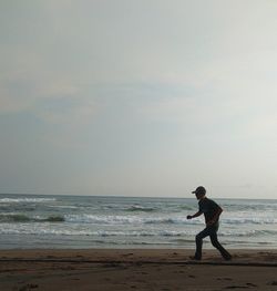 Side view of man on beach against sky