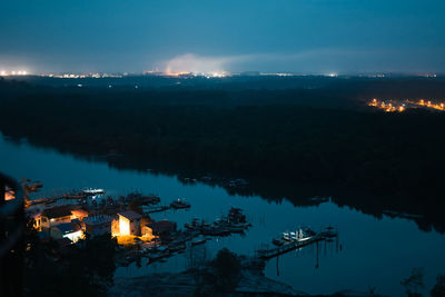 High angle view of illuminated reflection in lake against sky at night