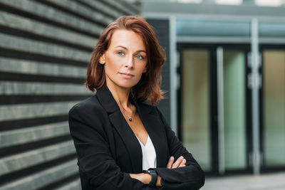 Portrait of young woman standing against wall