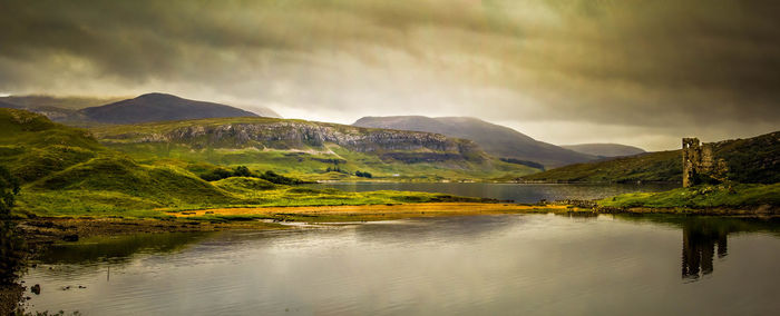 Scenic view of lake and mountains against cloudy sky