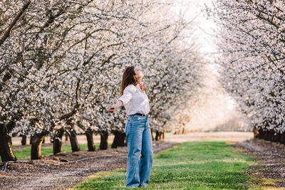 Woman enjoying springtime outdoors among blooming almond trees