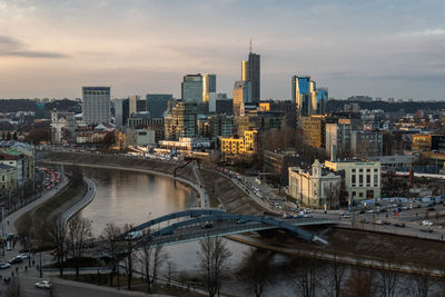 Bridge over river amidst buildings in city against sky