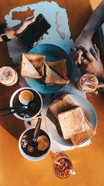 Cropped hands of people by breakfast on table 