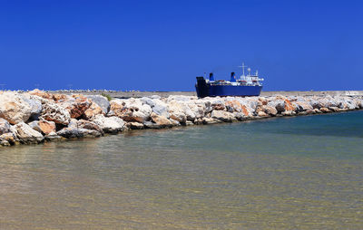 Boat moored at shore against blue sky