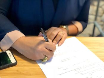 Midsection of man signing paper on table