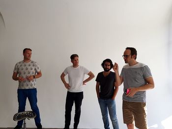 Business colleagues discussing while standing against white wall at creative office