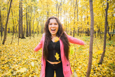 Smiling young woman standing in forest during autumn