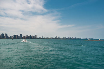 City at waterfront against cloudy sky