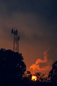 Low angle view of silhouette communications tower against sky during sunset