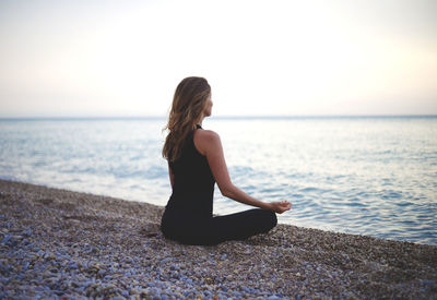 Full length of woman relaxing on shore against sea