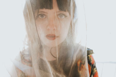 Close-up portrait of young woman against white background