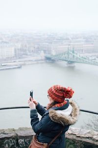 Side view of woman photographing with smart phone by river