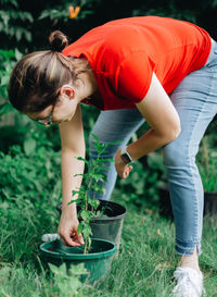 Young millennial mother  planting plants in garden being eco friendly and environmentally conscious