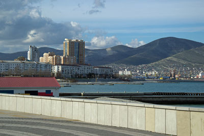 View of city by river against cloudy sky