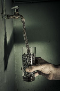 Midsection of person holding glass against wall