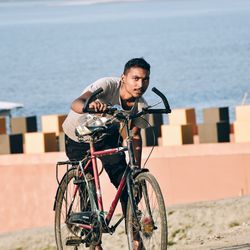 Young man riding bicycle on sea shore