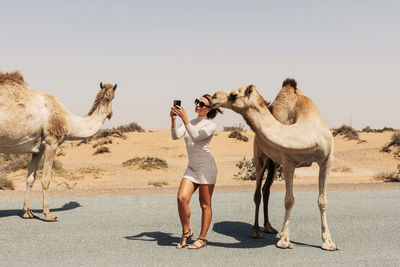 Rear view of woman walking on sand at desert against clear sky