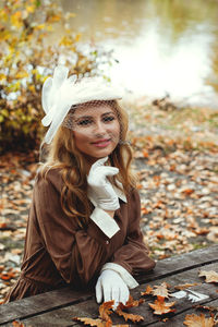 Young blonde woman in vintage clothes sitting in autumn park.