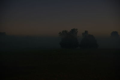 Silhouette trees on field against sky