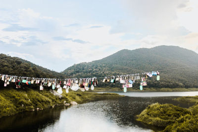 Group of people on mountain by lake against sky