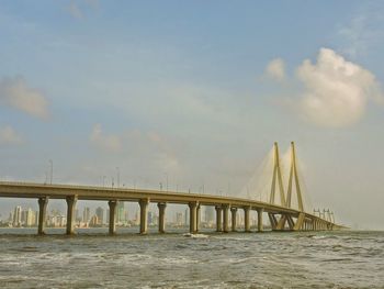 Bridge over river against cloudy sky