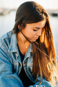 Young woman sitting at harbor during sunset