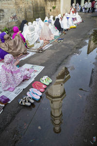 Reflection of mosque in puddle with people praying