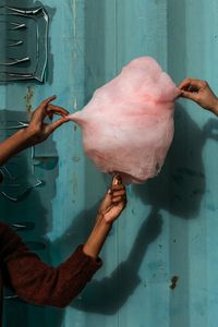 Cropped image of people holding cotton candy against corrugated iron