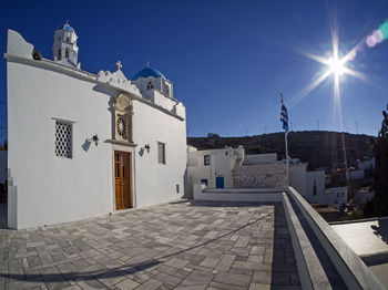 Footpath amidst buildings against blue sky on sunny day