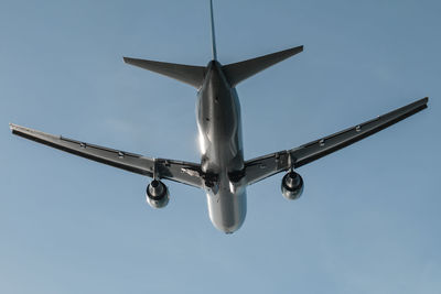 Low angle view of airplane flying against clear blue sky