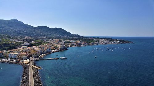 High angle view of sea and cityscape against clear sky