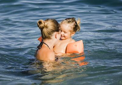 Mother enjoying with daughter in sea during summer