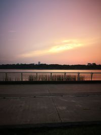 Road by sea against sky during sunset