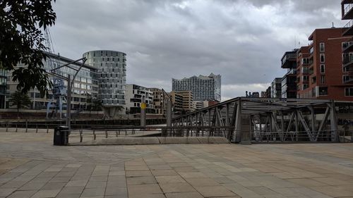 Footpath by buildings in city against sky