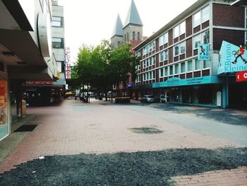 Road by buildings against sky in city