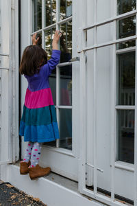 Rear view of woman standing by window