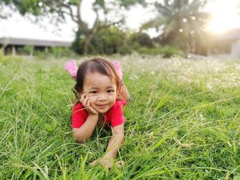 Portrait of cute baby girl lying on grassy field