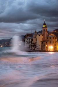 Buildings at waterfront against cloudy sky, camogli, italy