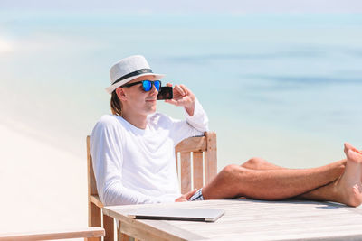 Side view of woman sitting at beach